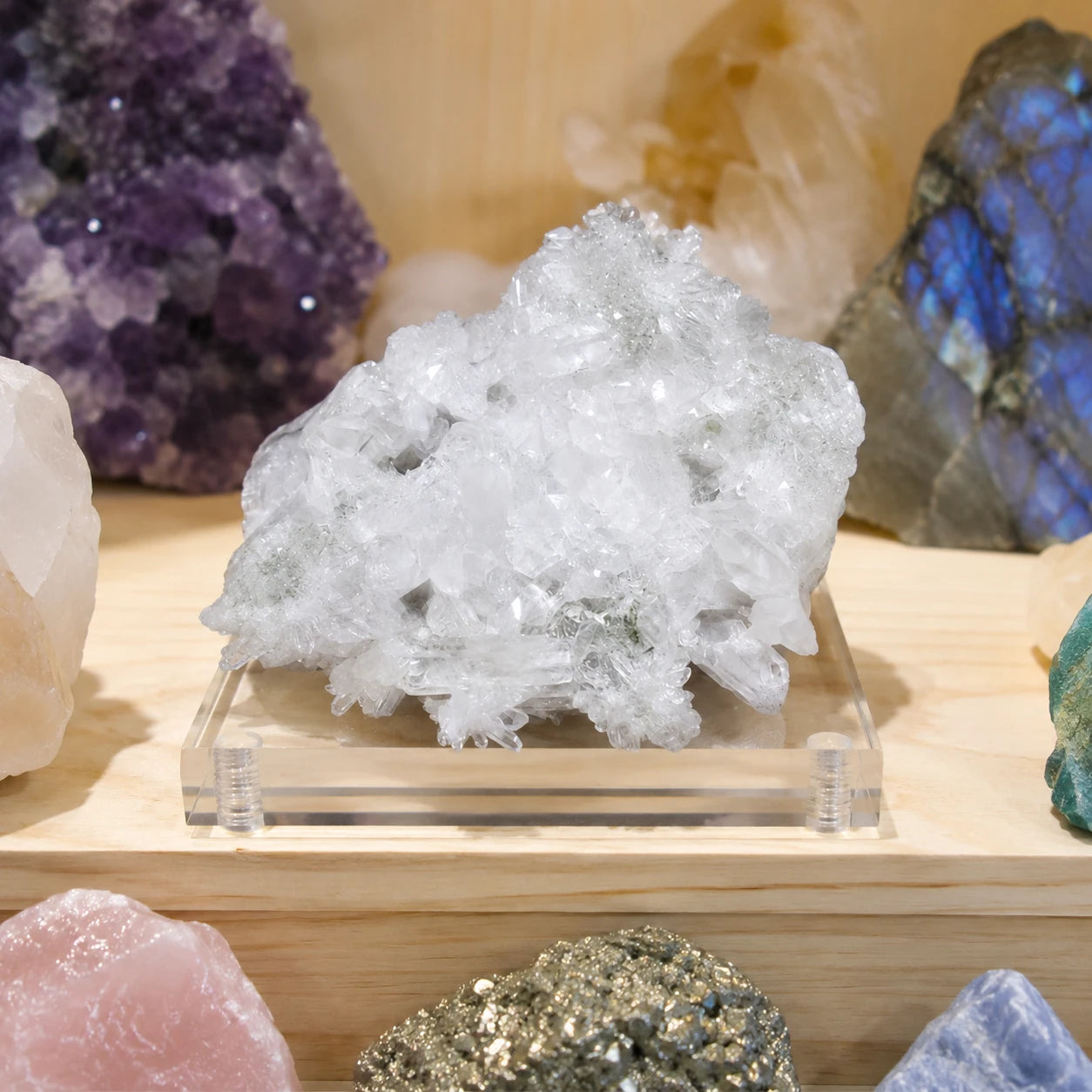 Druse de quartz naturel du Valais en Suisse présentée sur un socle dans une vitrine de minéraux, spécimen de 9 cm aux cristaux blancs translucides destiné à la collection et à la décoration.