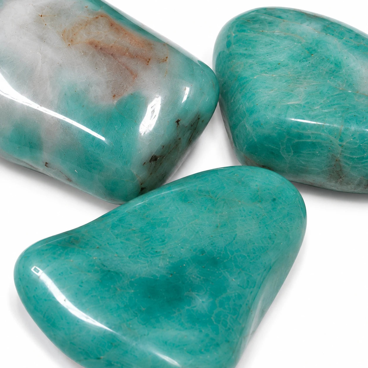 Gros plan sur trois amazonites roulées de Namibie montrant les détails de leur texture naturelle, leurs inclusions et leurs teintes bleu-vert caractéristiques.