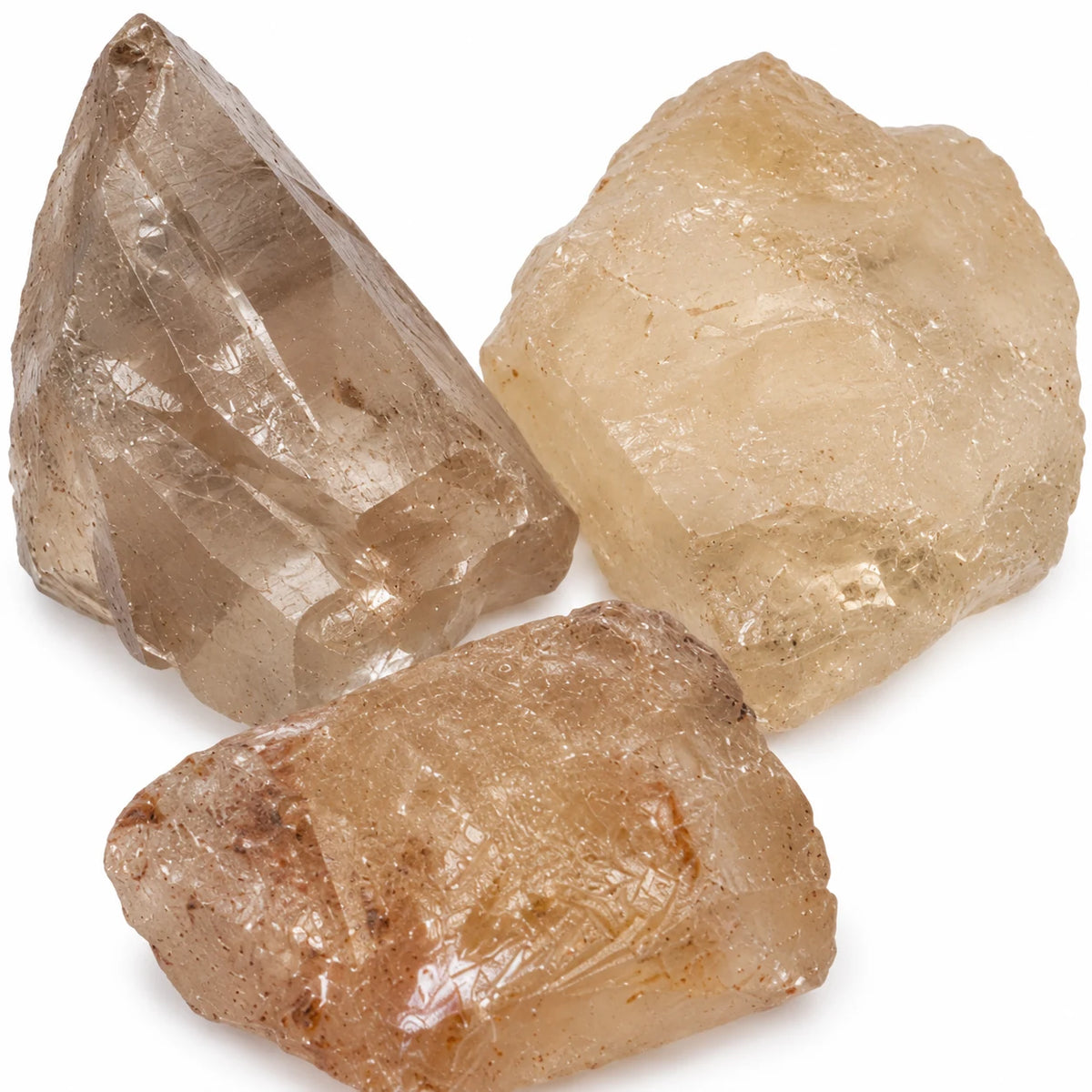 Zoom sur trois pierres brutes de citrine naturelle du Brésil, cristaux aux nuances champagne, beige doré et translucides