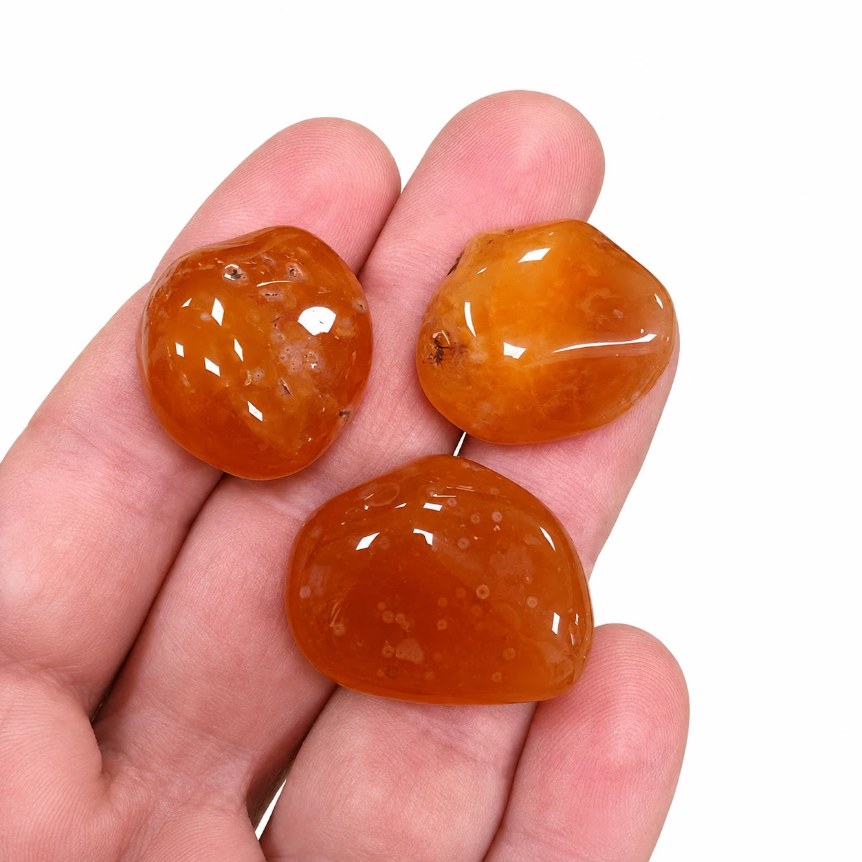 Pierre naturelle cornaline roulée du Botswana tenue en main – aperçu de la taille réelle de pierres roulées naturelles de 2 à 3 cm aux teintes orange chaleureuses.