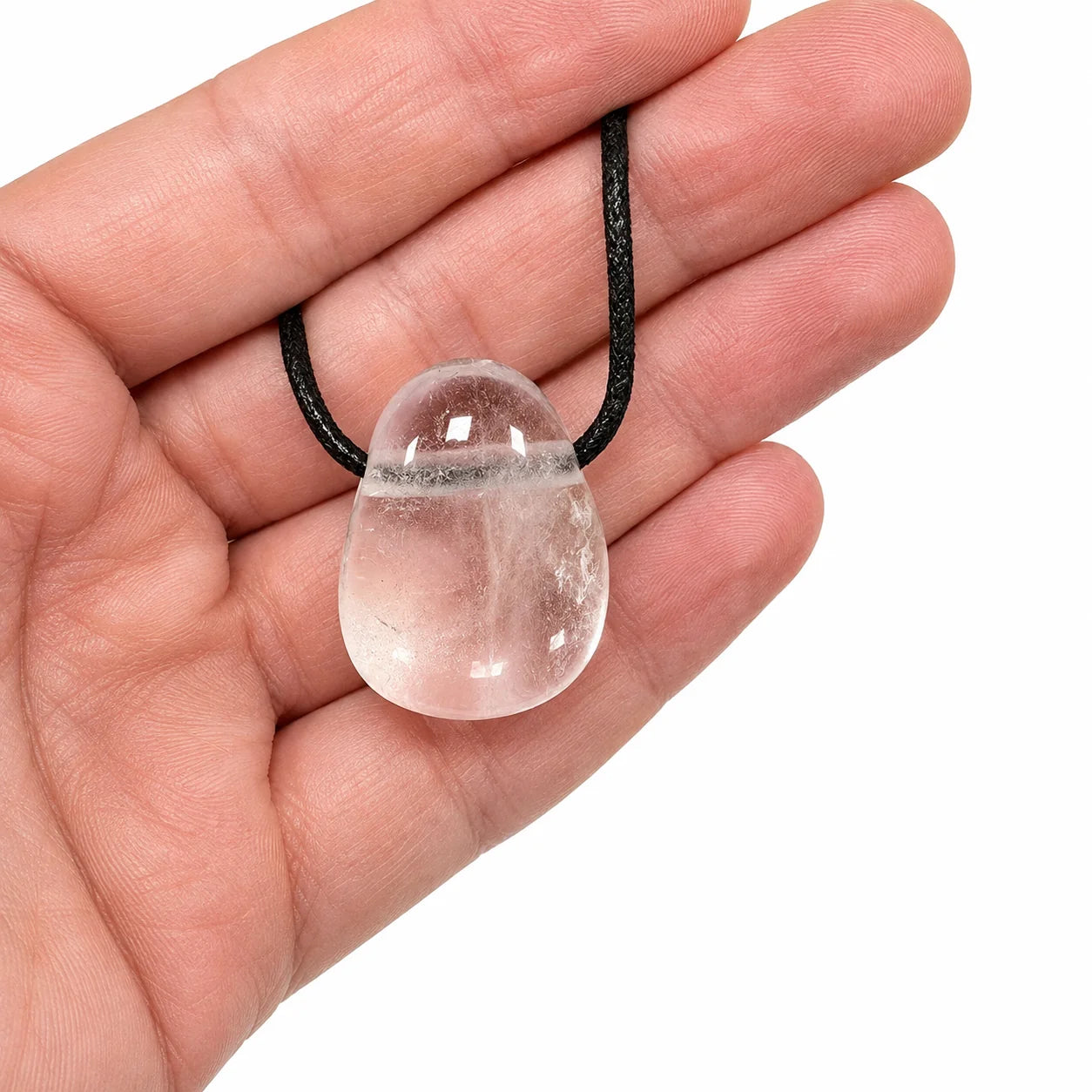 Pendentif cristal de roche de Madagascar en pierre percée naturelle présenté dans la main, quartz transparent poli de 2 à 3 cm avec cordon noir, pierre authentique.