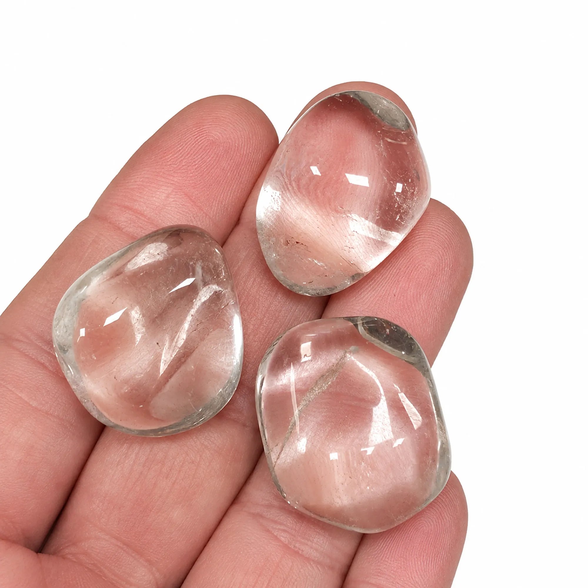 Pierre naturelle cristal de roche roulé du Brésil – trois pierres roulées en quartz transparent présentées dans la main pour illustrer leur taille de 2 à 3 cm et leur aspect naturel.