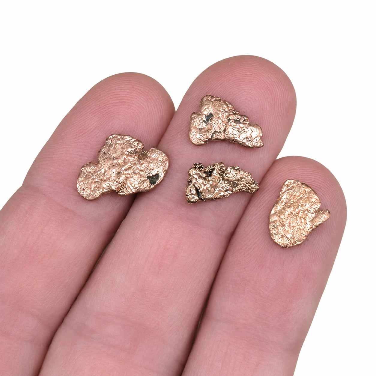 Véritables pépites de cuivre natif du Michigan, États-Unis, présentées dans une main pour illustrer leur taille réelle. Petits spécimens de cuivre naturel massif aux reflets métalliques, idéals pour la collection de minéraux et la lithothérapie.