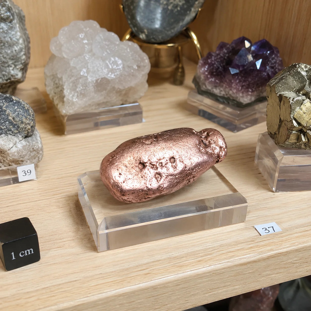 Pierre roulée en cuivre natif du Keweenaw, Michigan, États-Unis, exposée sur un socle dans une vitrine de minéraux. Spécimen naturel de collection aux reflets métalliques caractéristiques du cuivre natif.