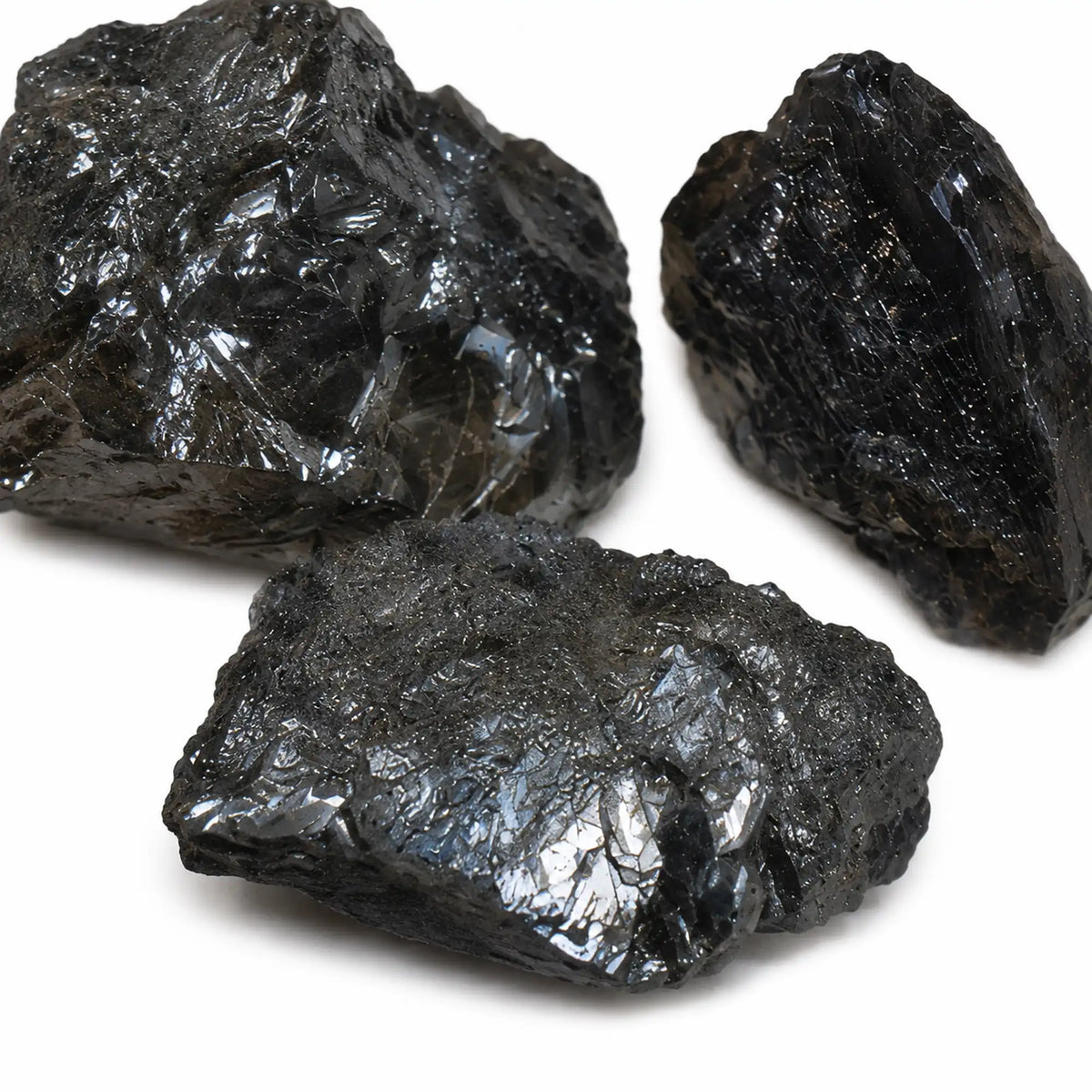 Zoom sur trois pierres brutes d’hématite spécularite de l’île d’Elbe, Italie, présentant un éclat métallique argenté et des surfaces cristallines