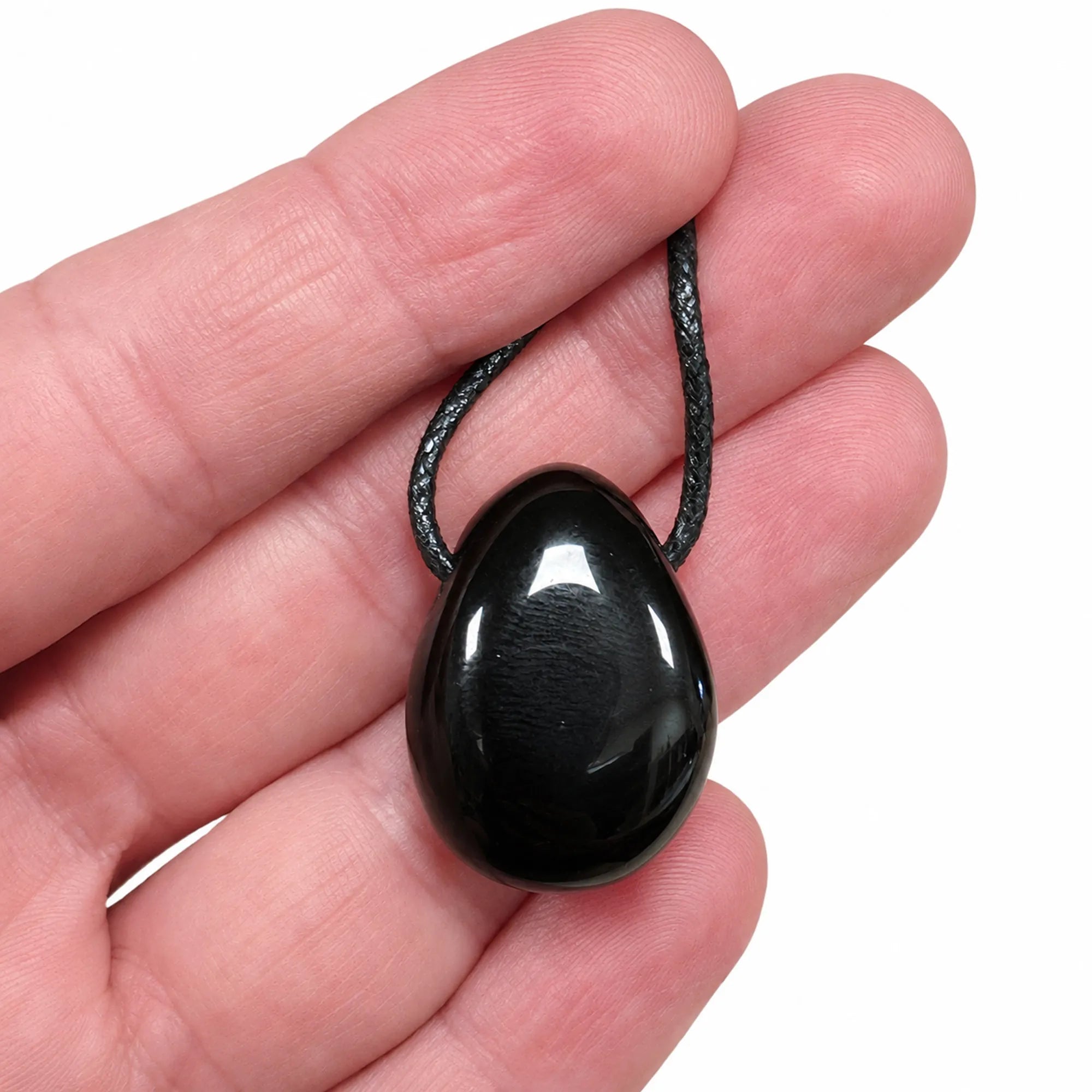 Pendentif obsidienne noire du Mexique en pierre percée naturelle présenté dans une main, galet poli noir brillant avec cordon noir, vue détaillée du bijou.