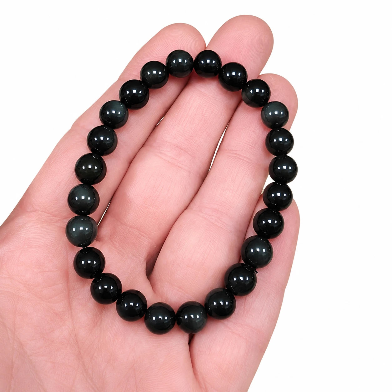 Bracelet en pierre véritable d'obsidienne œil céleste présenté dans la main, perles rondes de 8 mm mettant en valeur la taille réelle et les reflets naturels de la pierre.