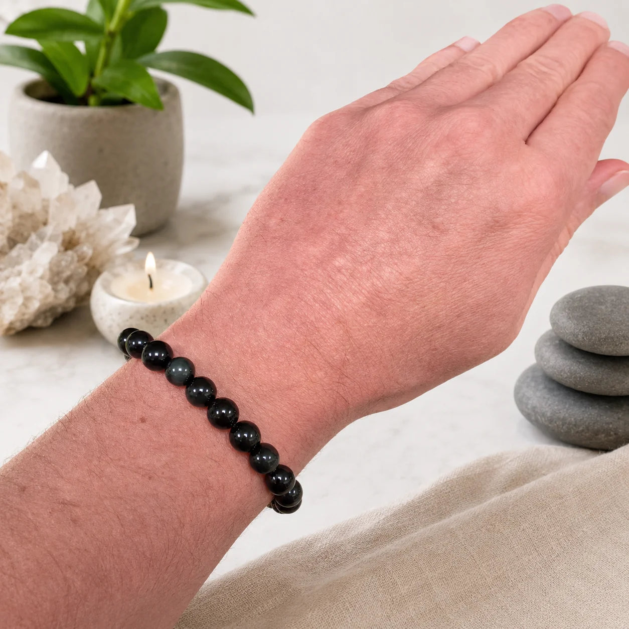 Bracelet en obsidienne œil céleste véritable porté au poignet, perles rondes de 8 mm aux reflets subtils, bijou en pierre naturelle pour homme ou femme.