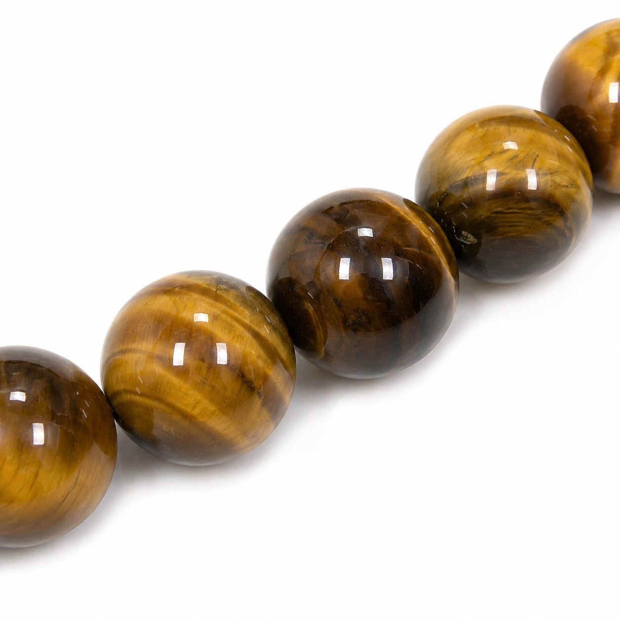 Gros plan des perles rondes de 6 mm d'un bracelet en Œil de tigre naturel, révélant la chatoyance, les reflets dorés et les nuances brunes caractéristiques de cette pierre utilisée en lithothérapie.