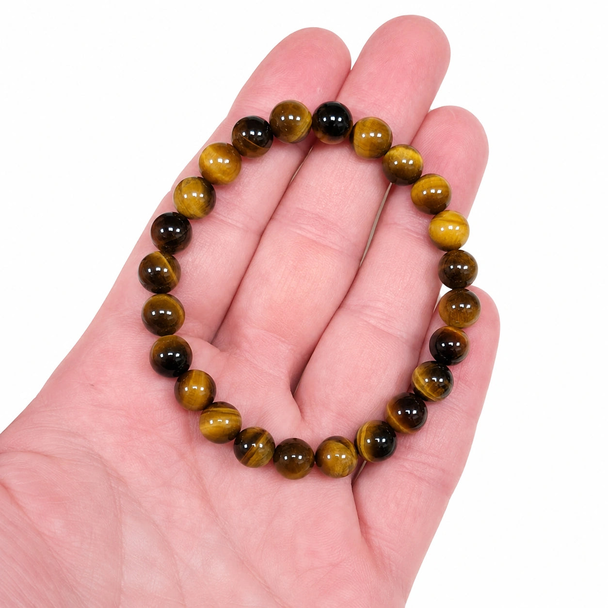 Bracelet en véritable Œil de tigre 8 mm porté au poignet dans une ambiance zen avec minéraux et encens, bijou en pierre naturelle aux reflets chatoyants, adapté aux femmes et aux hommes.