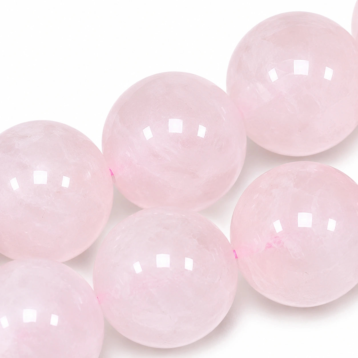 Gros plan sur les perles rondes de 8 mm d'un bracelet en véritable quartz rose, révélant la transparence, les inclusions naturelles et la douce teinte rose de cette pierre naturelle.