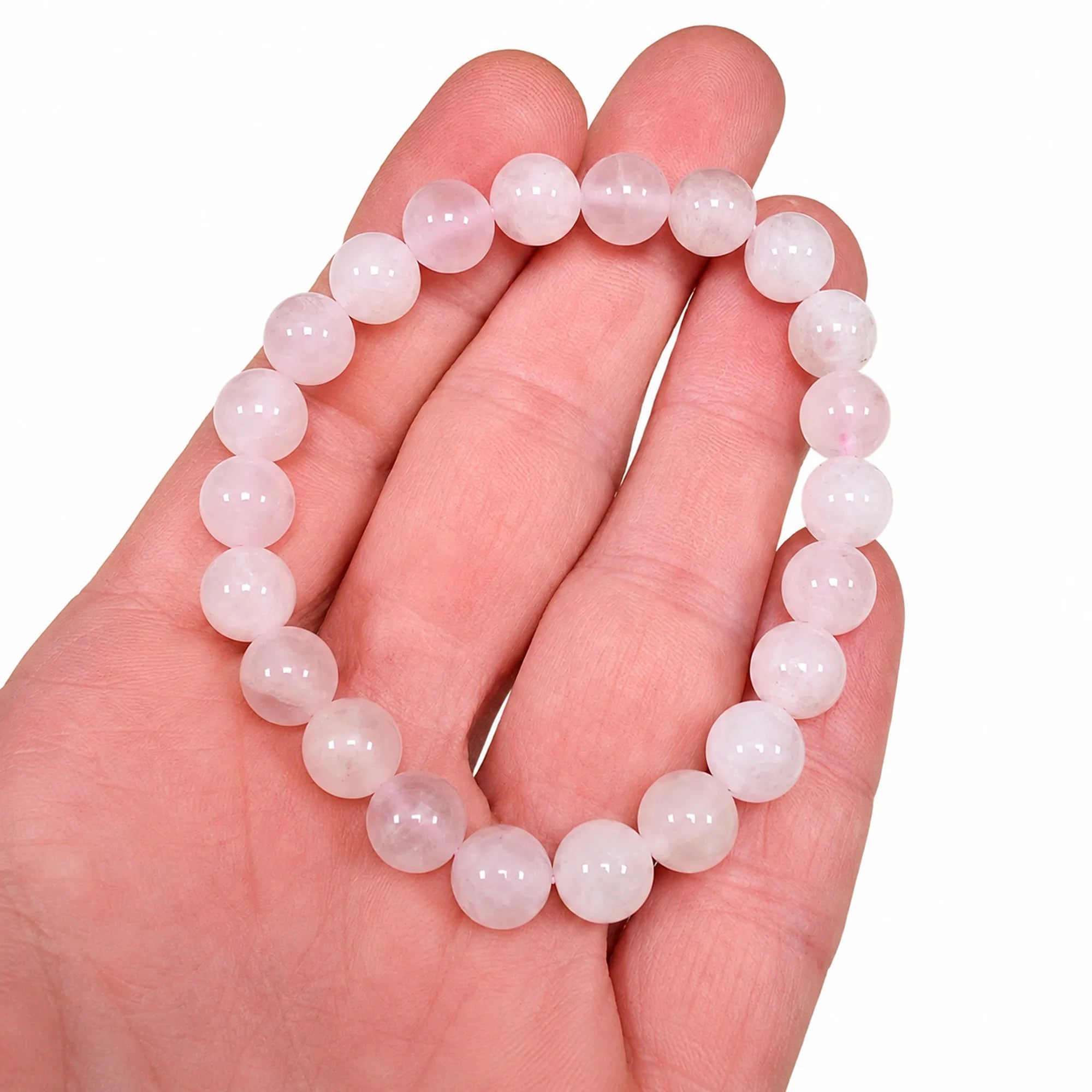 Bracelet en véritable quartz rose avec perles rondes de 8 mm présenté dans une main afin d'illustrer sa taille réelle, sa couleur naturelle et la finition polie de chaque perle.