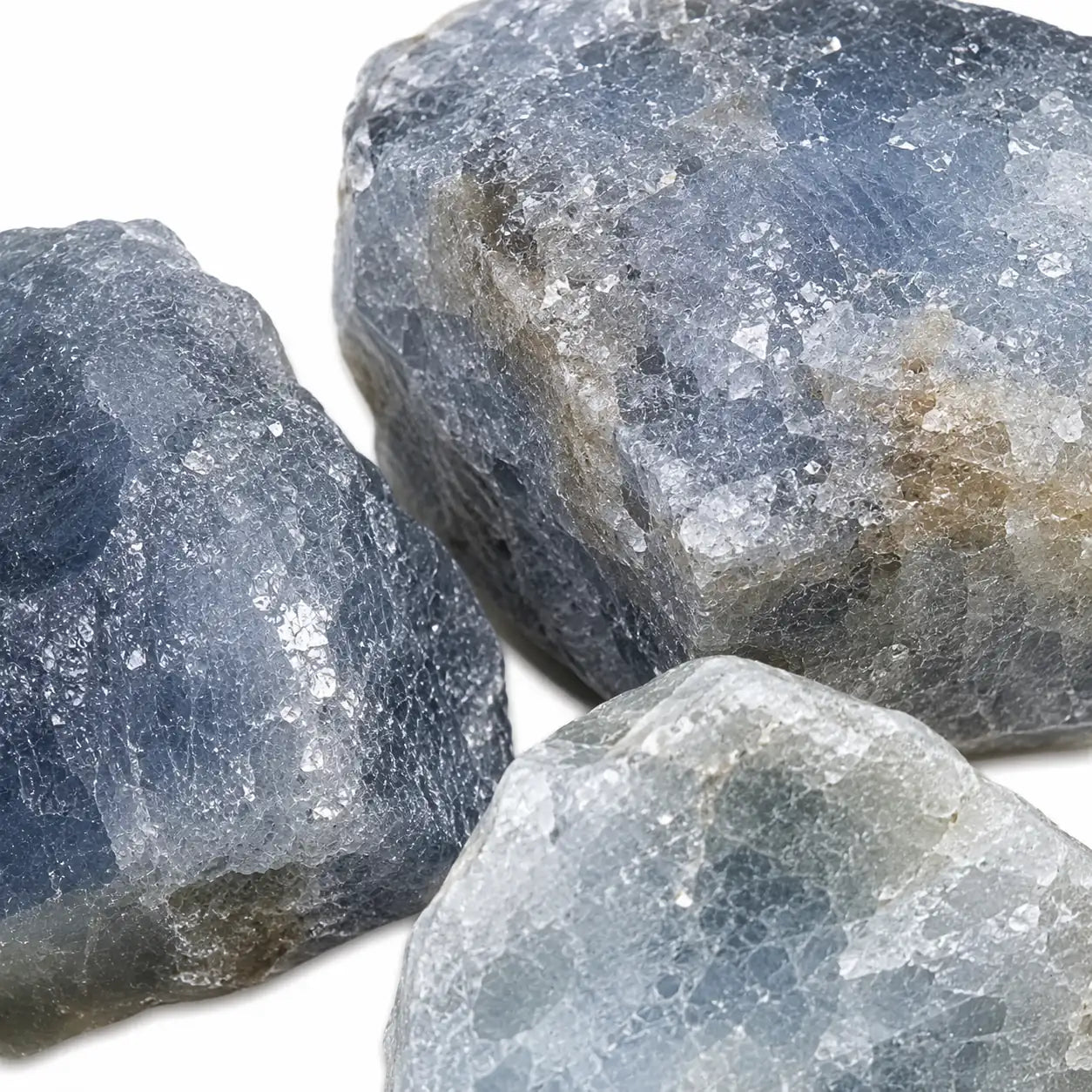 Gros plan sur trois pierres brutes de saphir bleu de Madagascar révélant leur cristallisation naturelle, leurs nuances bleu acier et leur texture minérale authentique.