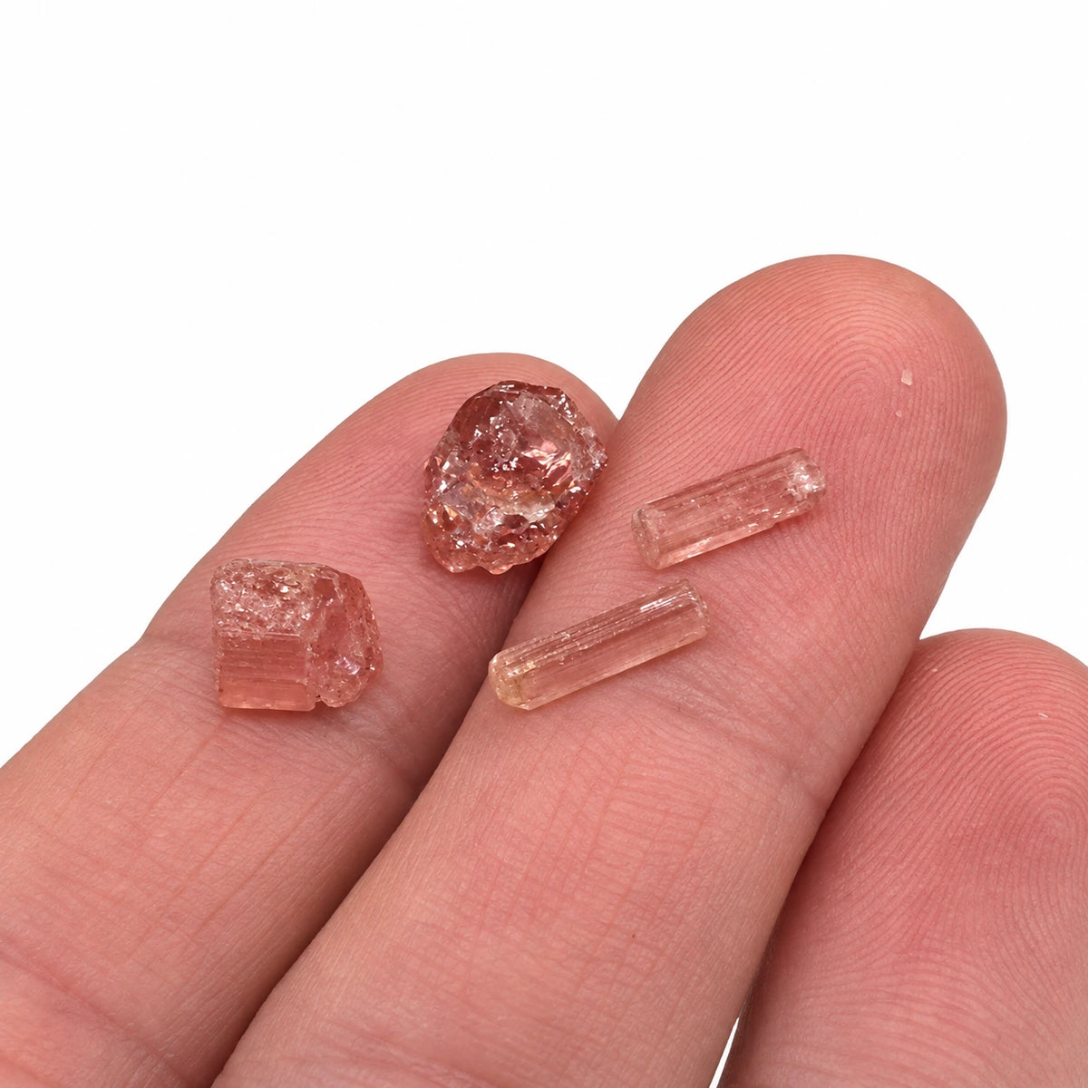 Petits cristaux bruts de tourmaline rose rubellite de Madagascar présentés dans la main, mettant en évidence leur petite taille et leurs nuances naturelles
